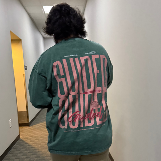 Person wearing a green sweatshirt with pink text walking down a hallway.