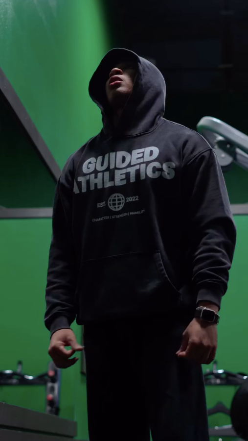 Person wearing a black hoodie with 'Guided Athletics' text in a gym setting